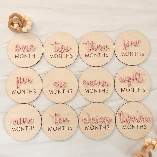 Wooden milestone discs with months printed on them, arranged in a row.