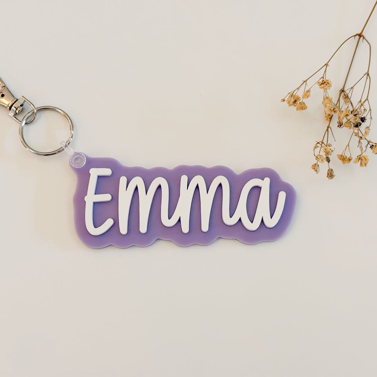 Solid color acrylic name keychain spelling Emma with silver keyring.