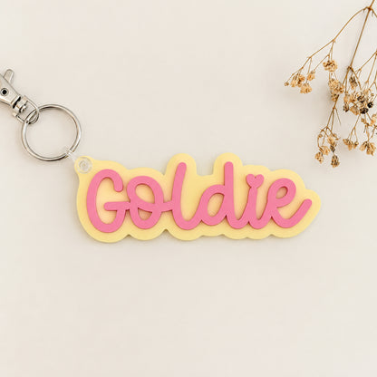 Solid color acrylic name keychain spelling Goldie with silver keyring.