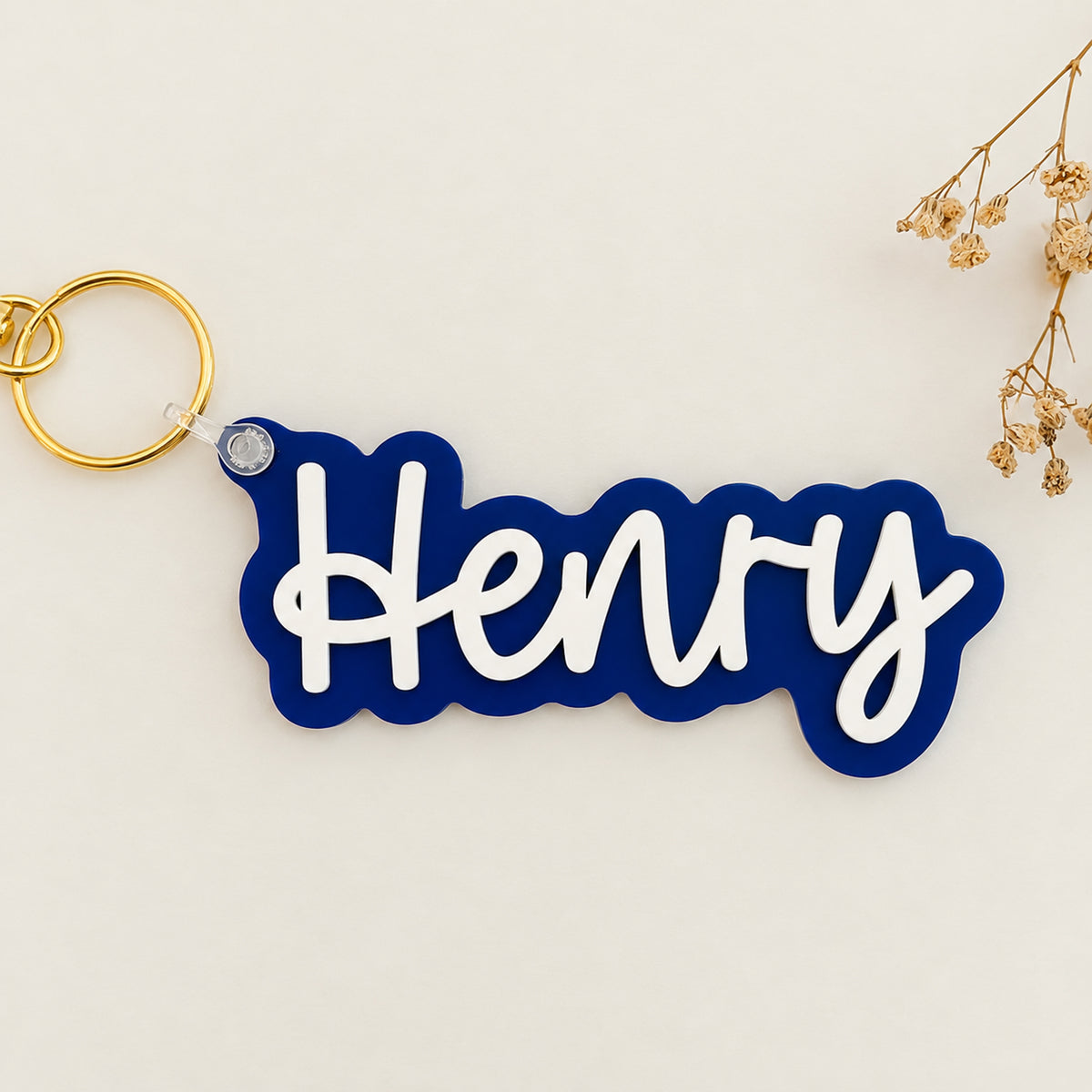 Solid blue color acrylic name keychain spelling Henry with gold keyring.