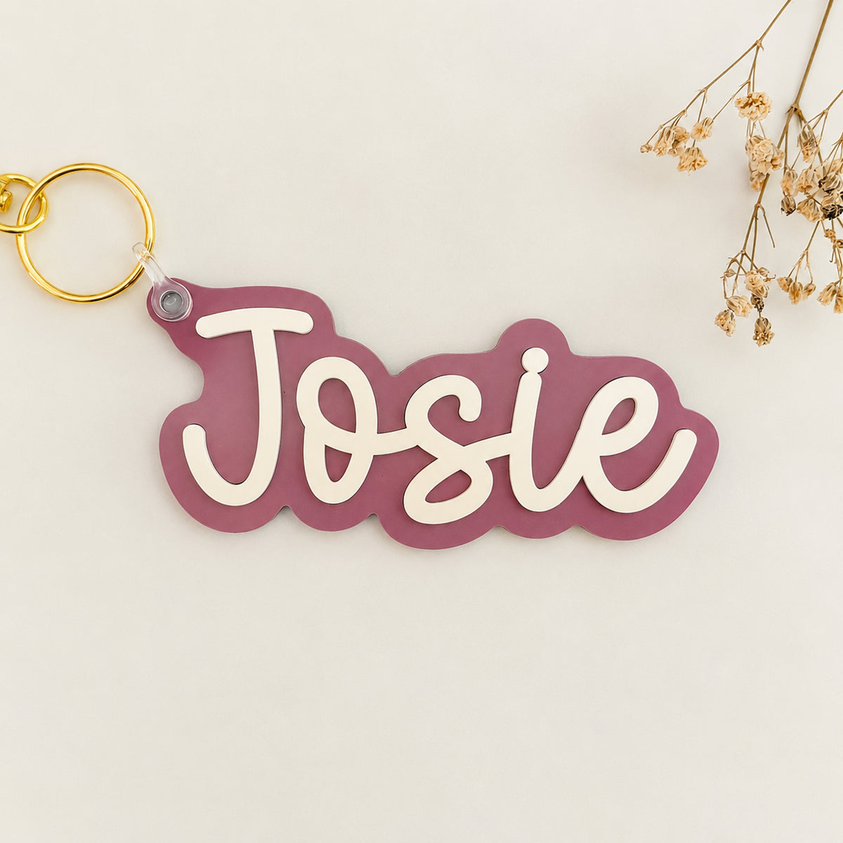 Solid color acrylic name keychain spelling Josie with gold keyring.